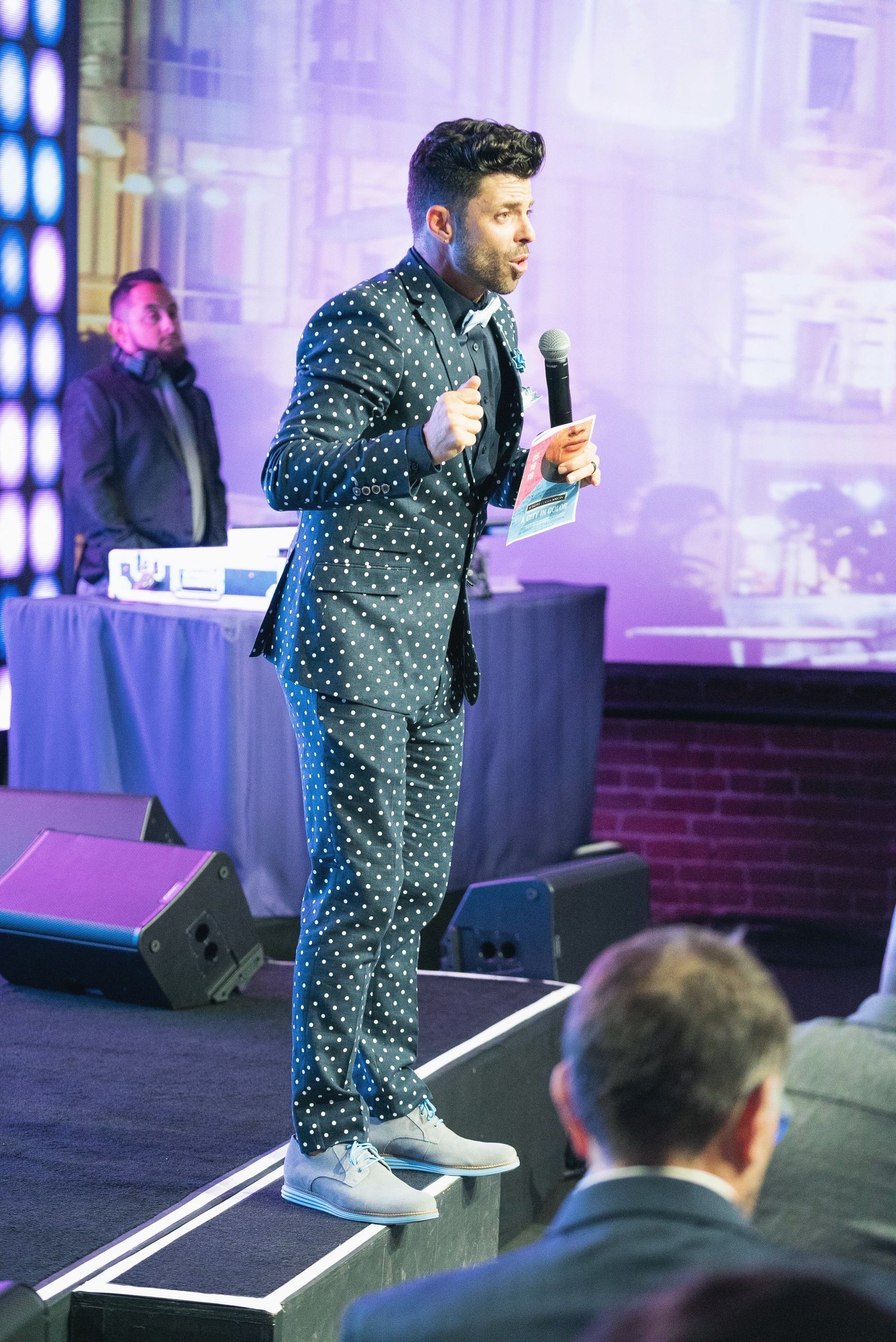 A man in a suit is standing on a stage holding a microphone.