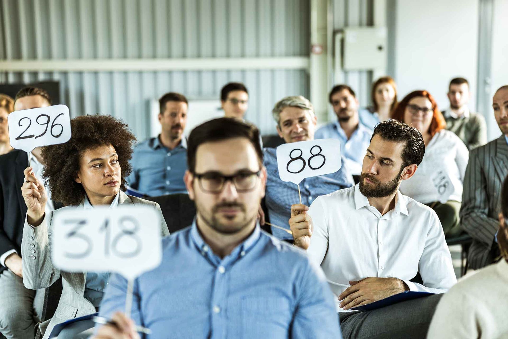 A group of people are sitting in a room holding signs with numbers on them.