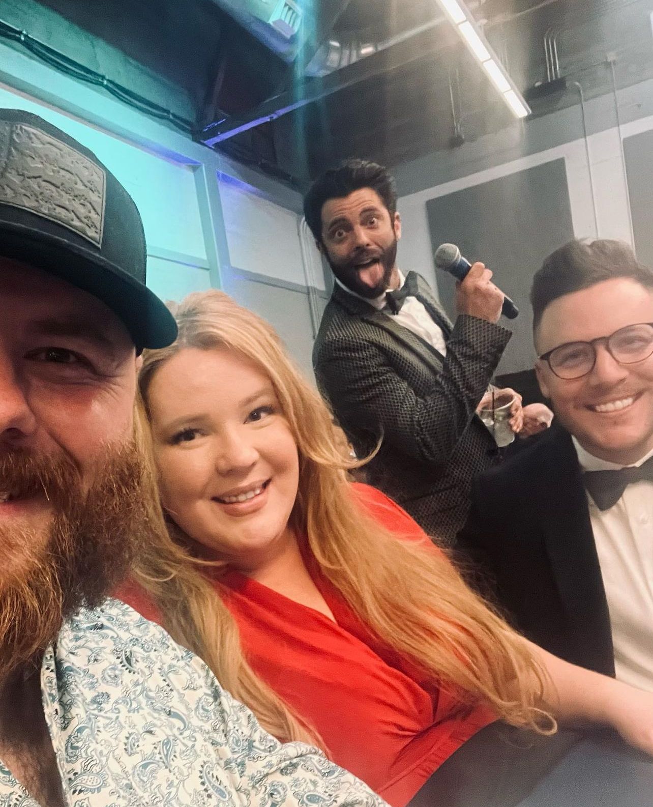 A group of people are posing for a picture and one of them is holding a microphone.