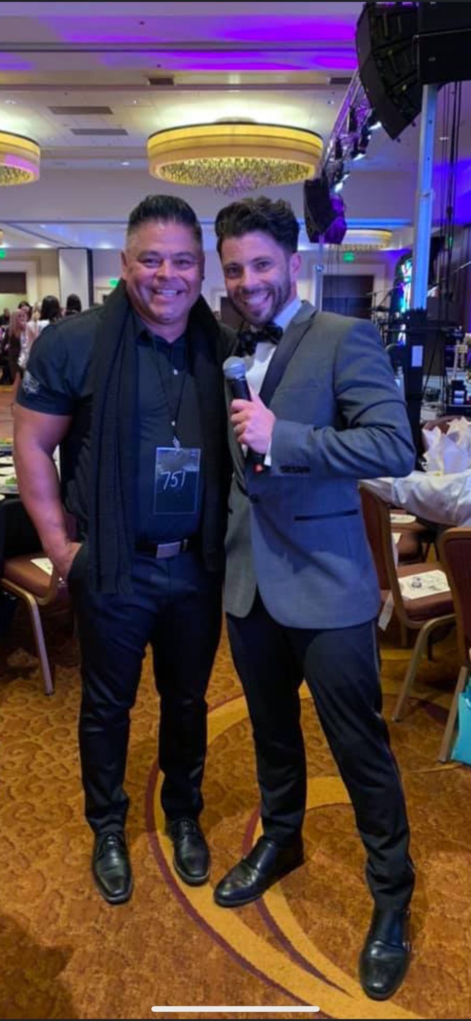 Two men are standing next to each other in a room holding microphones.