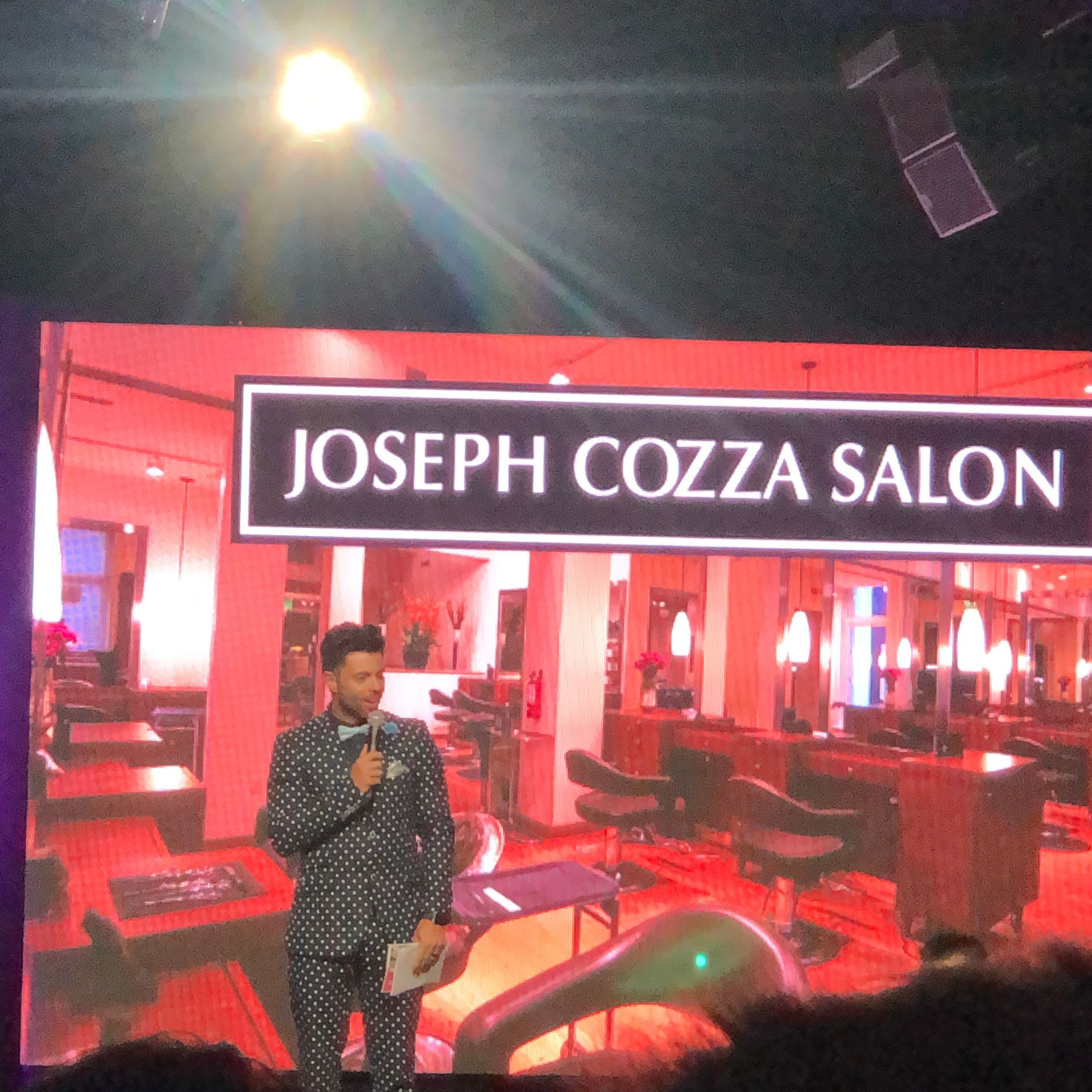 A man stands in front of a sign that says Joseph Cozza Salon
