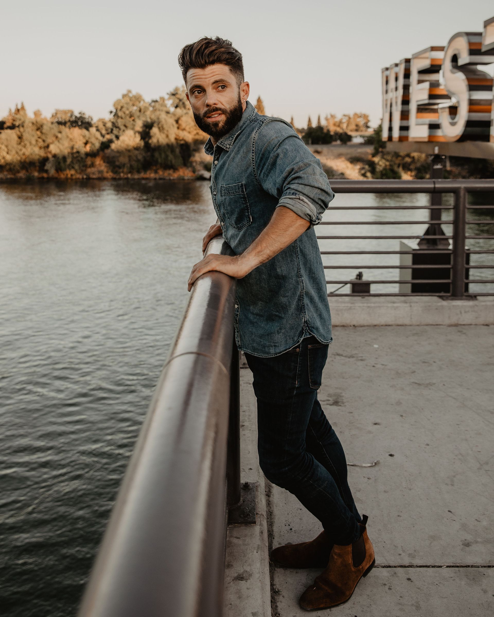 A man leaning on a railing overlooking a body of water.