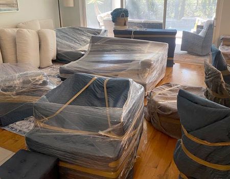 Furniture wrapped in plastic and strapped with tape, ready for moving. Interior setting.