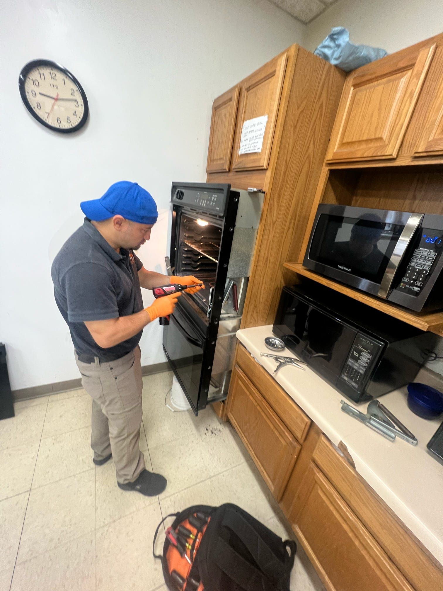 A man is working on an oven in a kitchen.