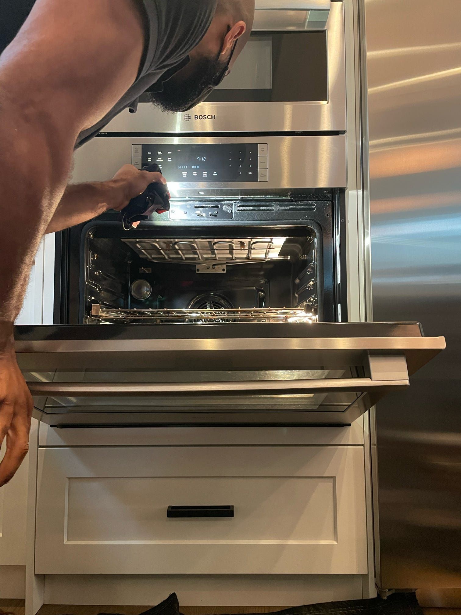 A man is opening the door of a stainless steel oven.