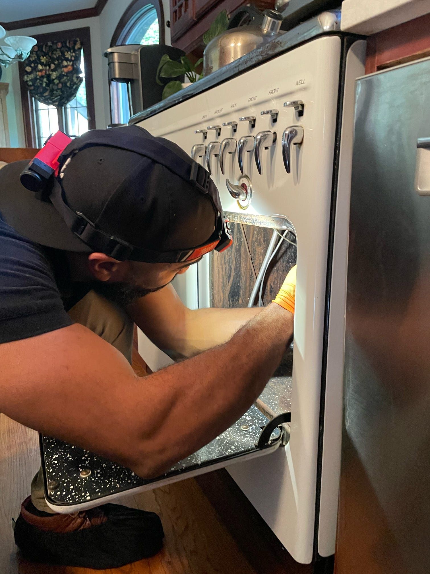 A man is working on a stove in a kitchen.