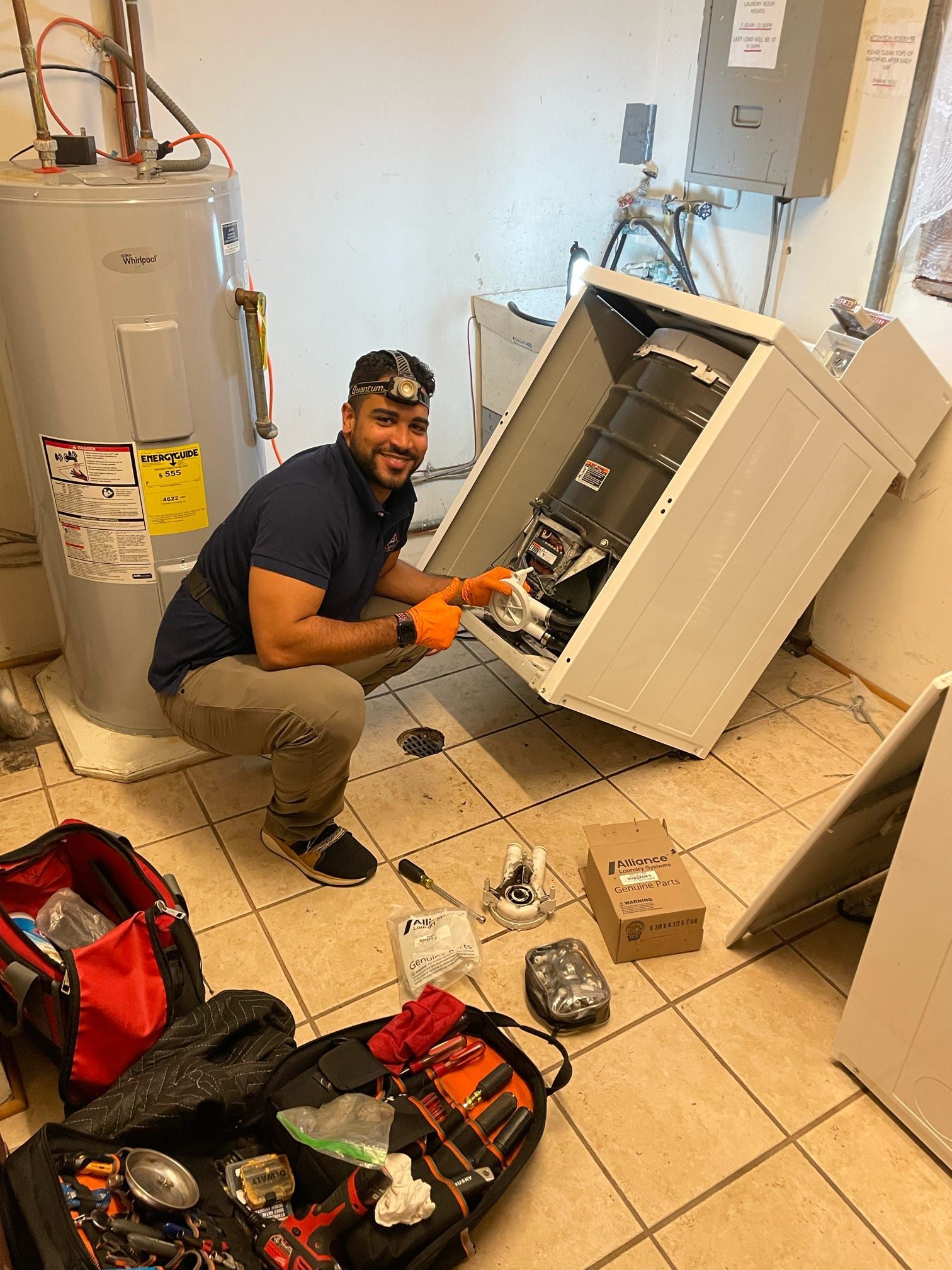 A man is working on a washing machine in a laundry room.