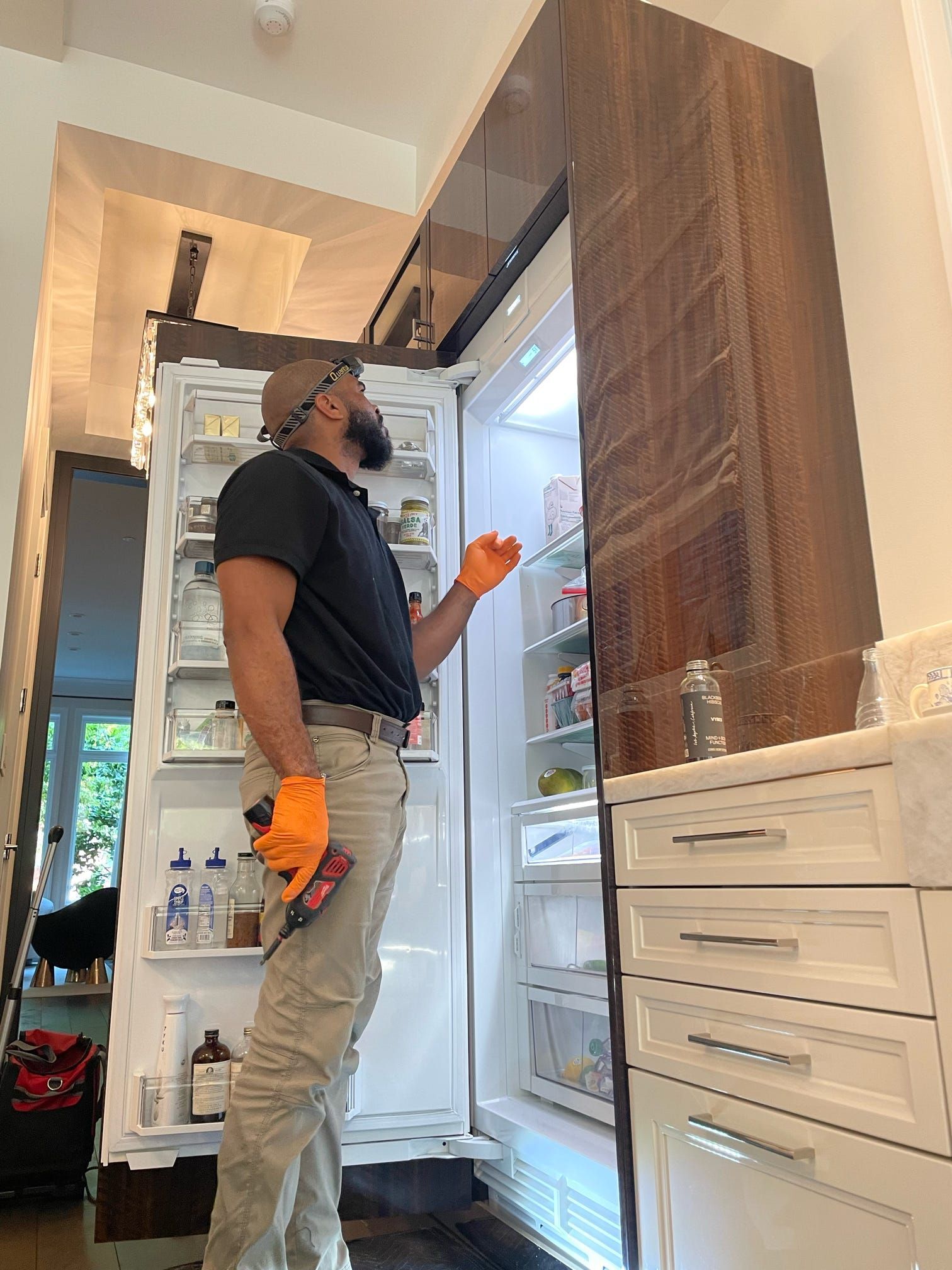 A man is working on a refrigerator in a kitchen.