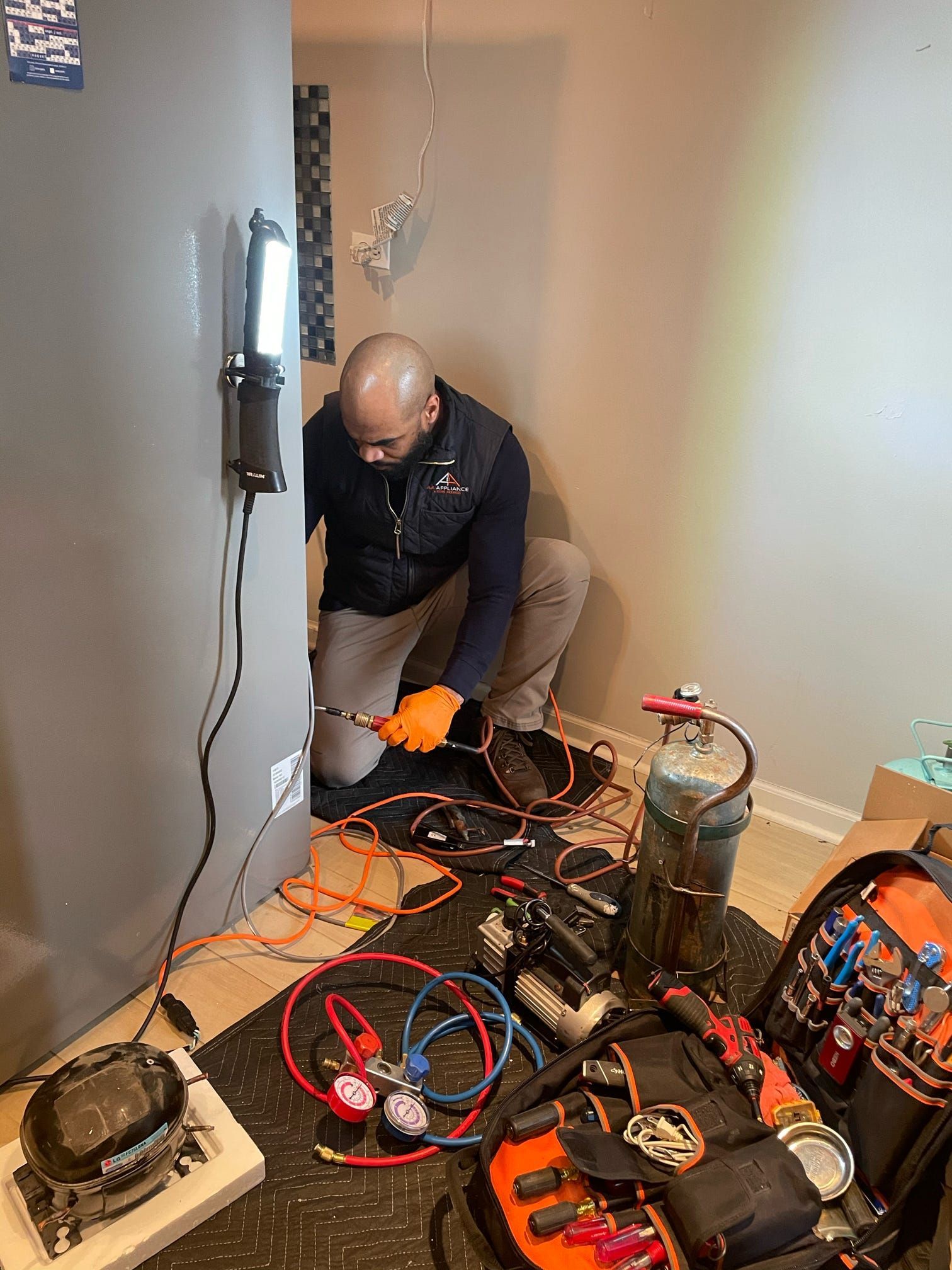 A man is working on a refrigerator in a room.