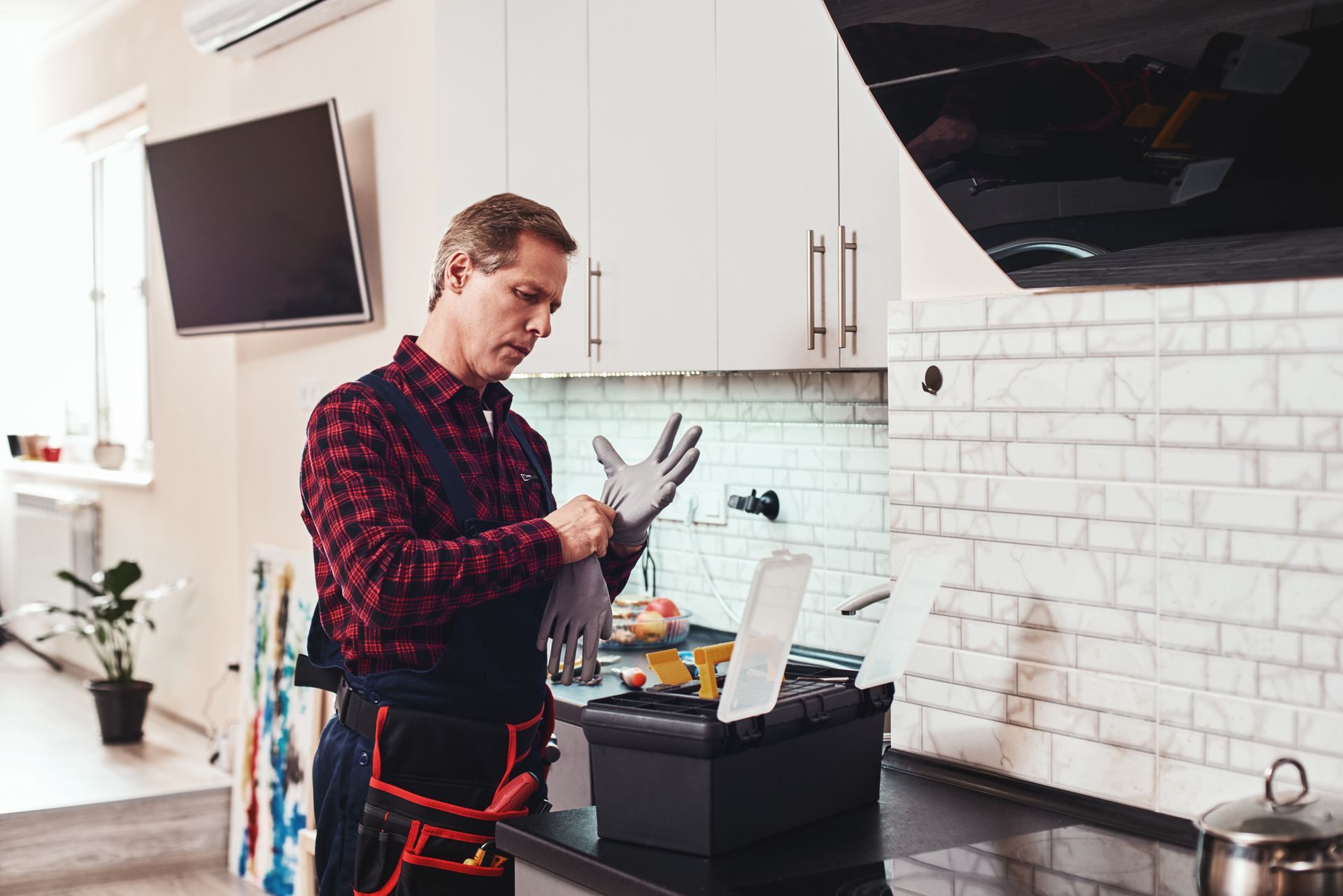 A man is putting on gloves in a kitchen.