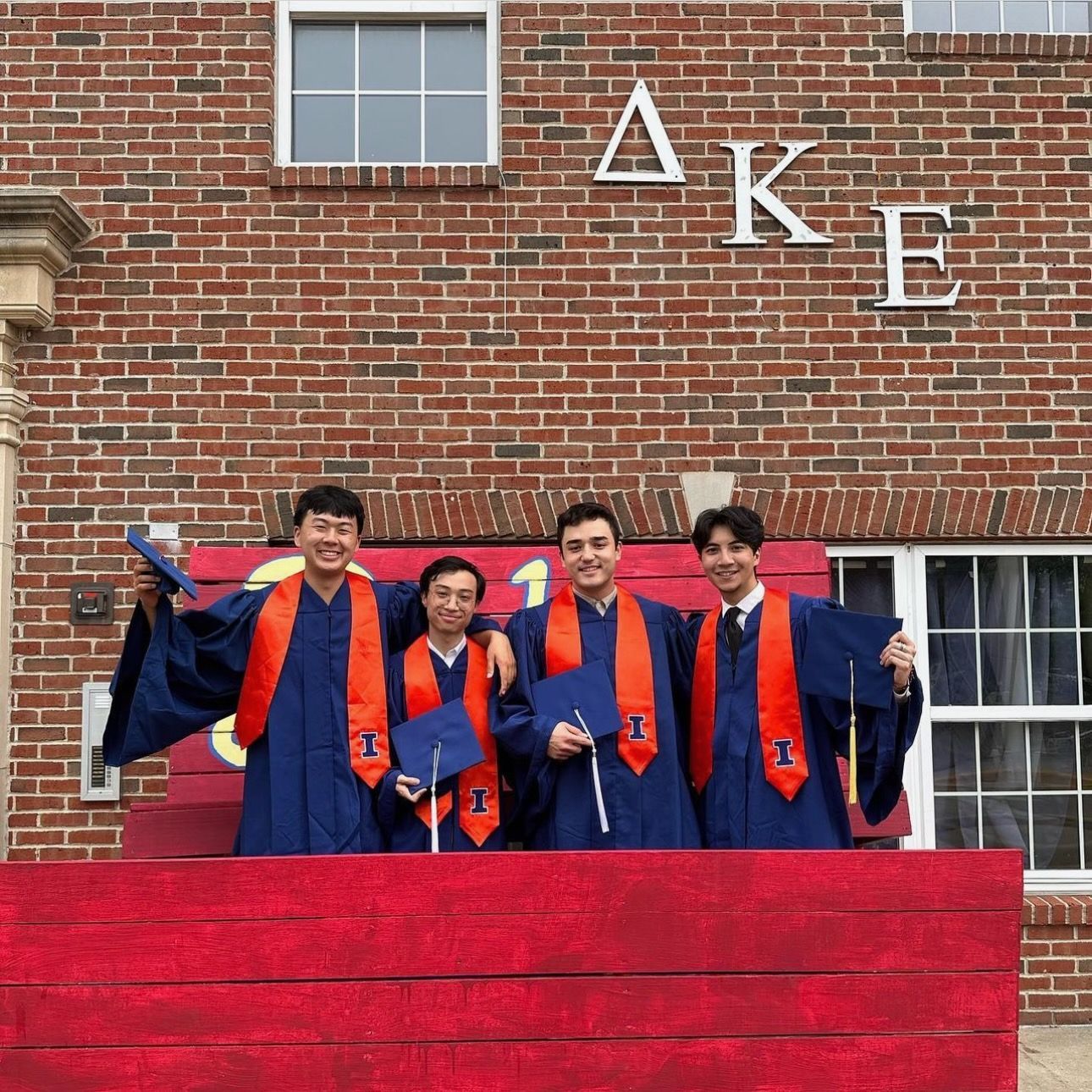 Three DKE Graduates standing in front of their fraternity house