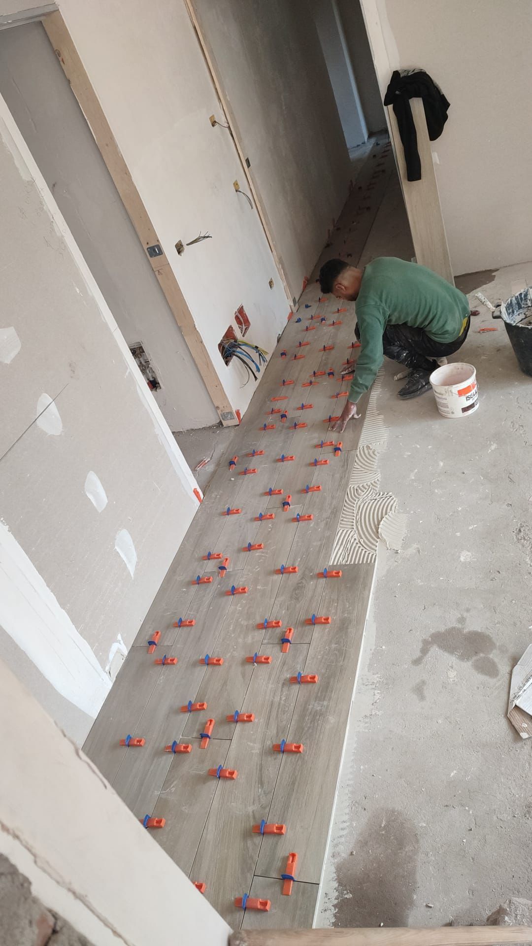 un uomo sta posando dei mattoni su un muro con una cazzuola.