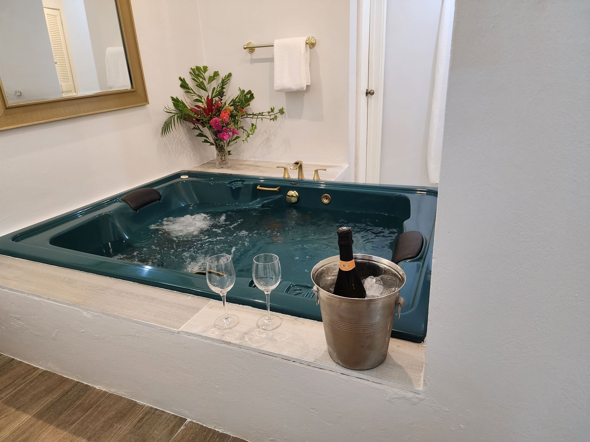 A bathtub with a bucket of ice and a bottle of wine in it.