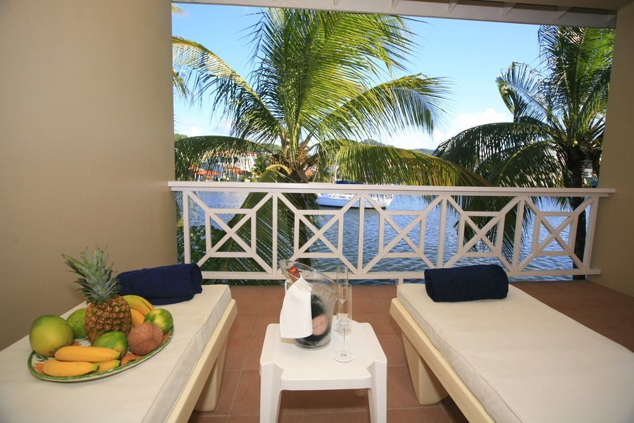 A balcony with two lounge chairs and a table with a bottle of champagne on it.