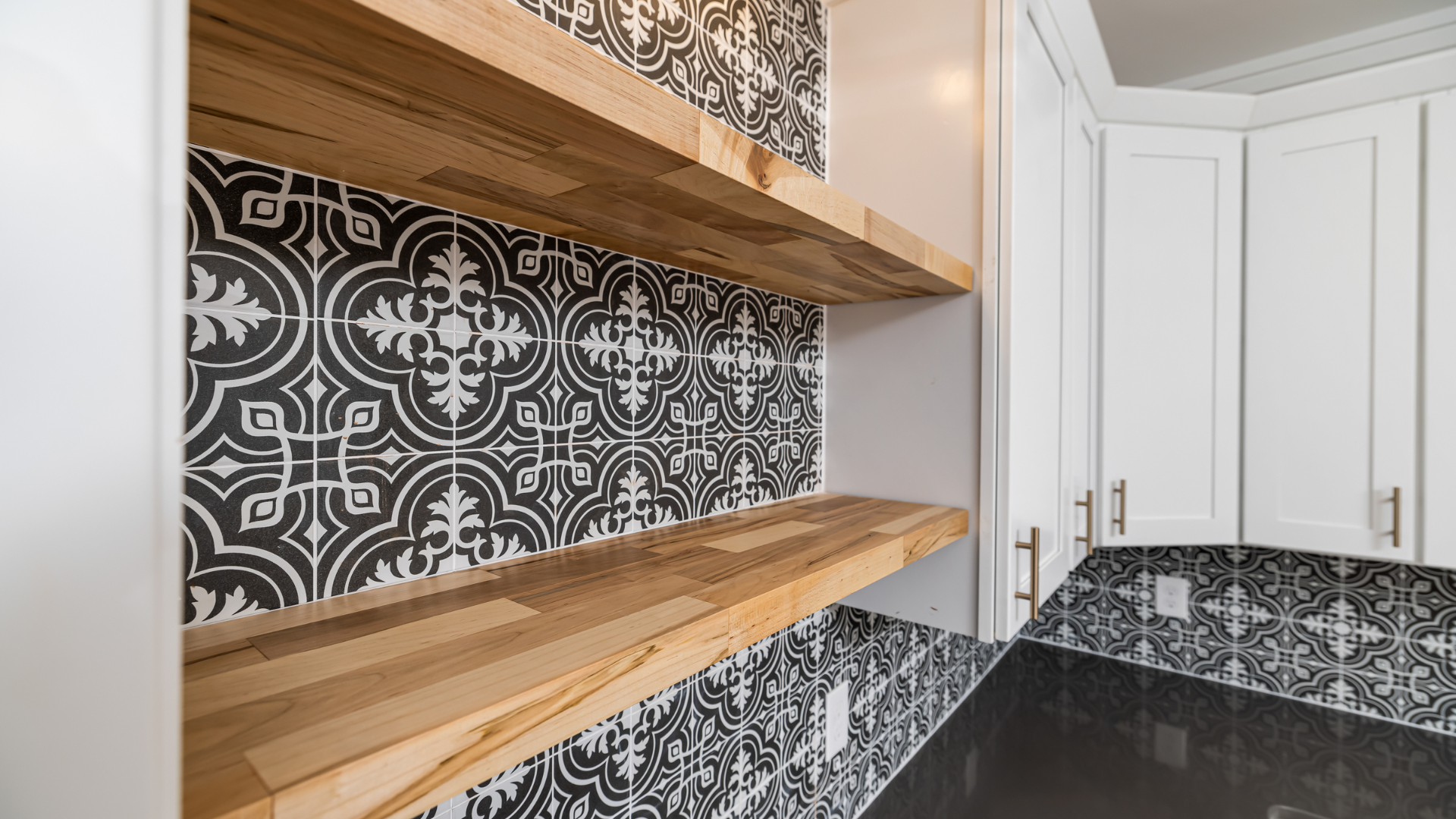 A kitchen with black and white tiles and wooden shelves.