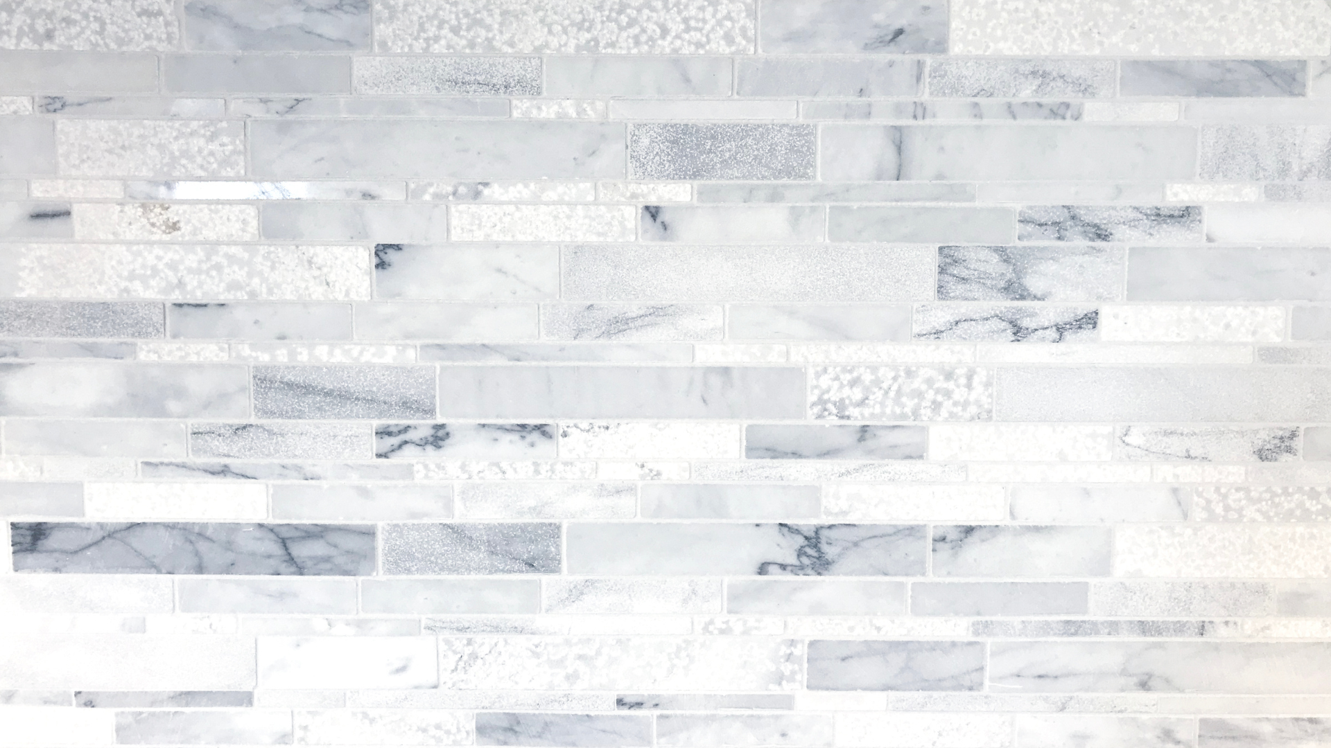 A close up of a white marble tile wall.