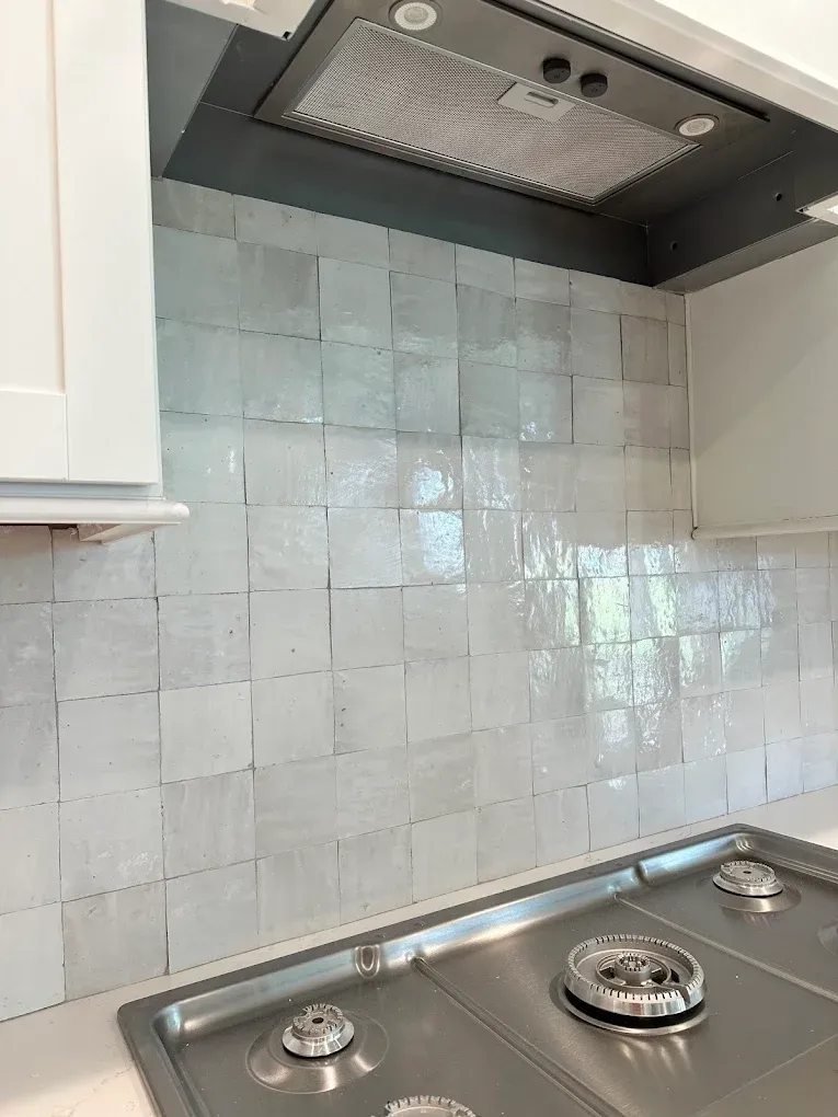 A kitchen with a stove top oven and a hood.