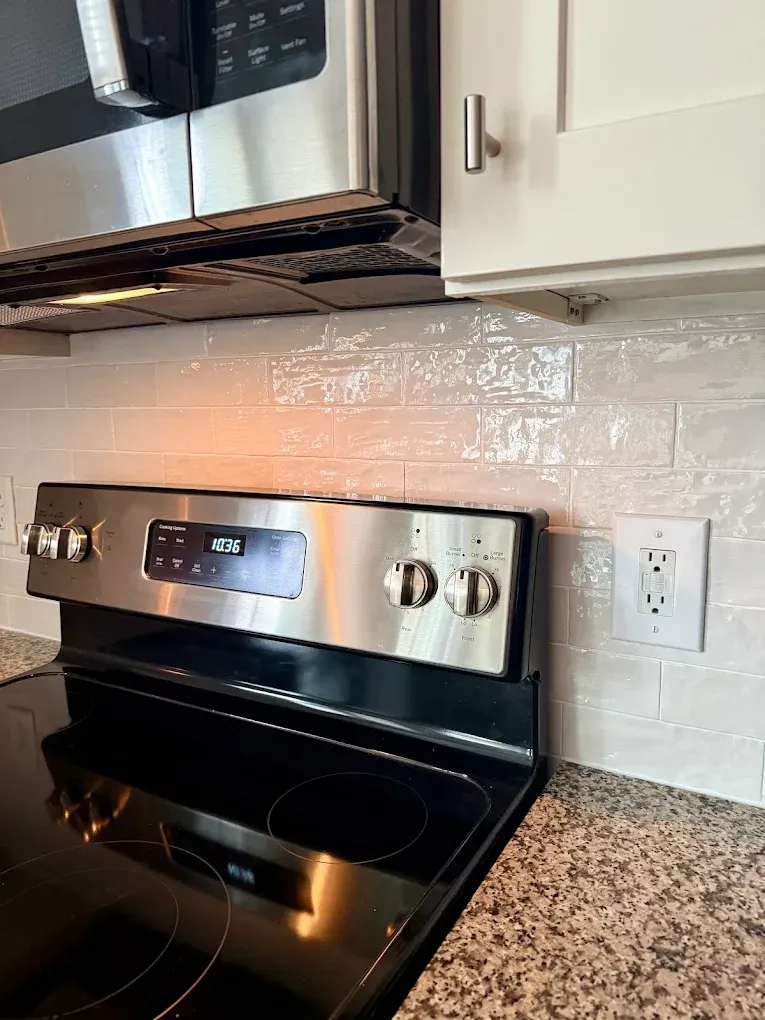 A stove top oven is sitting on top of a granite counter in a kitchen.
