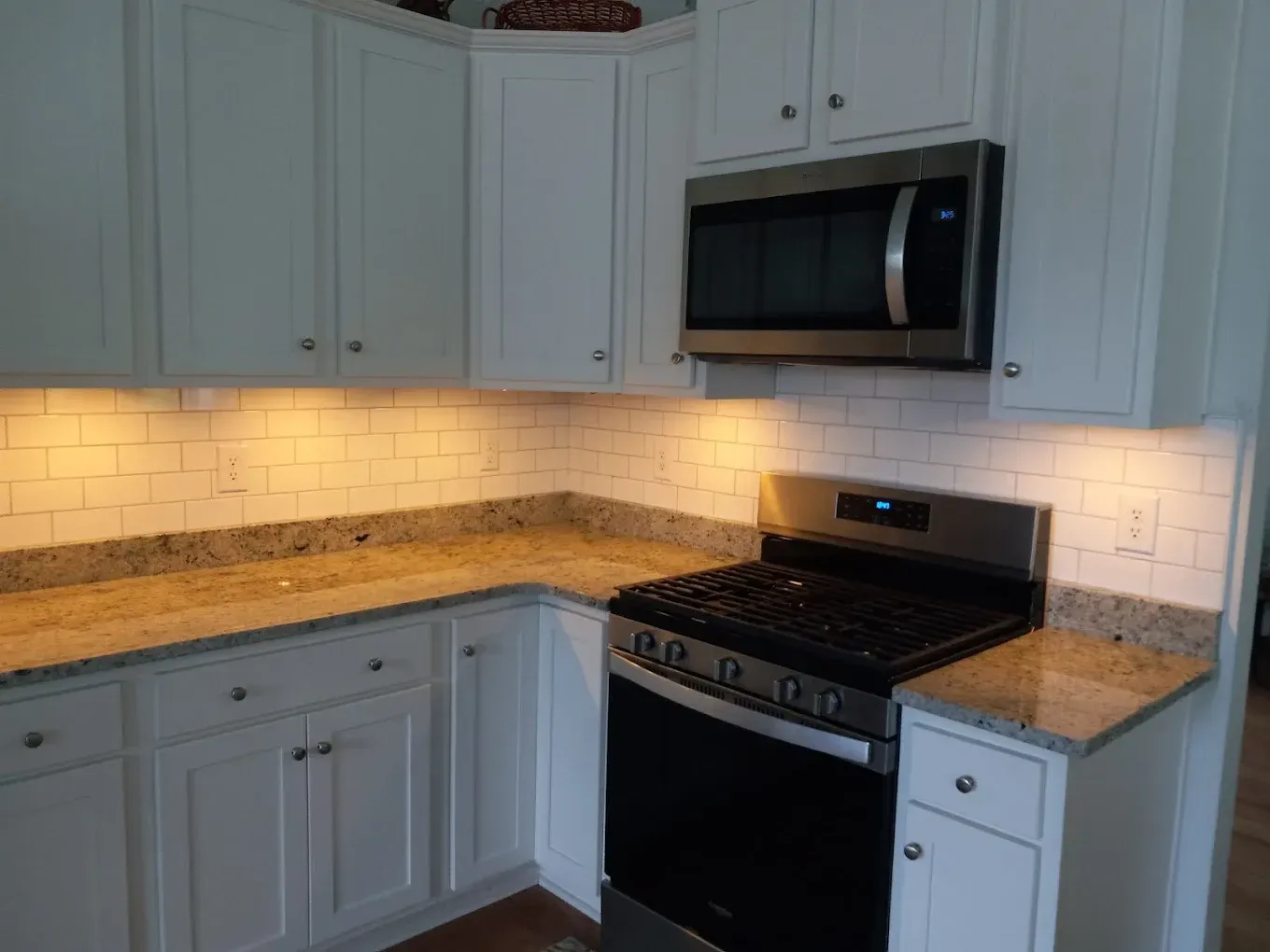 A kitchen with white cabinets and a stove and microwave