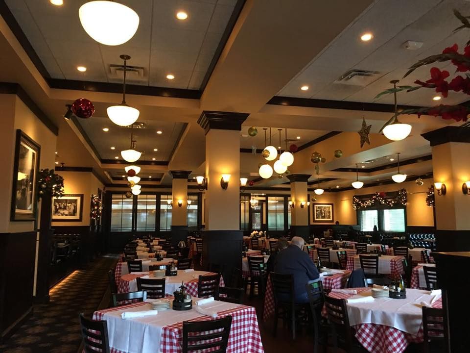 A dining room with tables covered in red-and-white checkered cloths, warm ambient lighting, and dark wood accents.