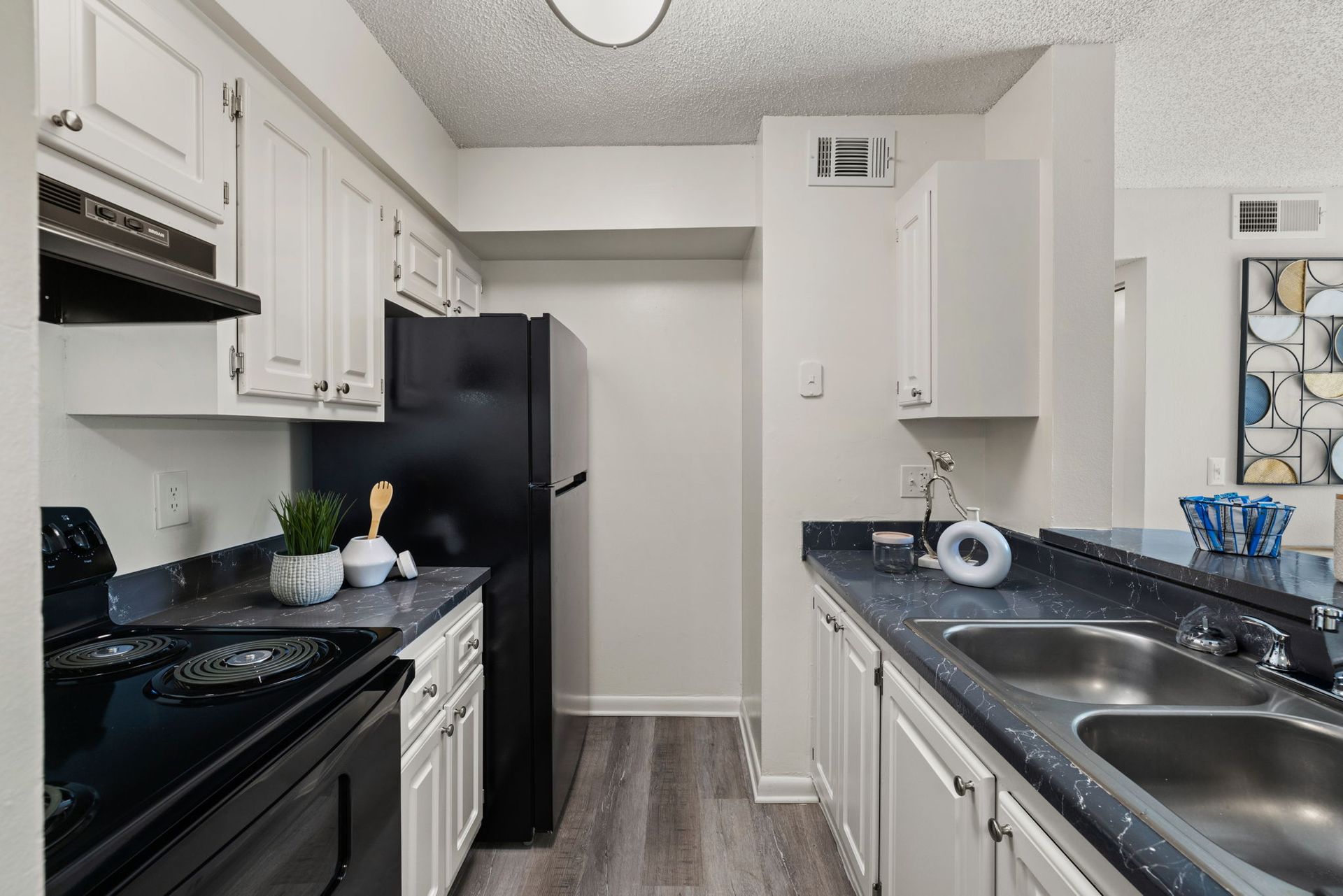 Kitchen with white cabinets, black appliances, blue countertops, and a double sink.