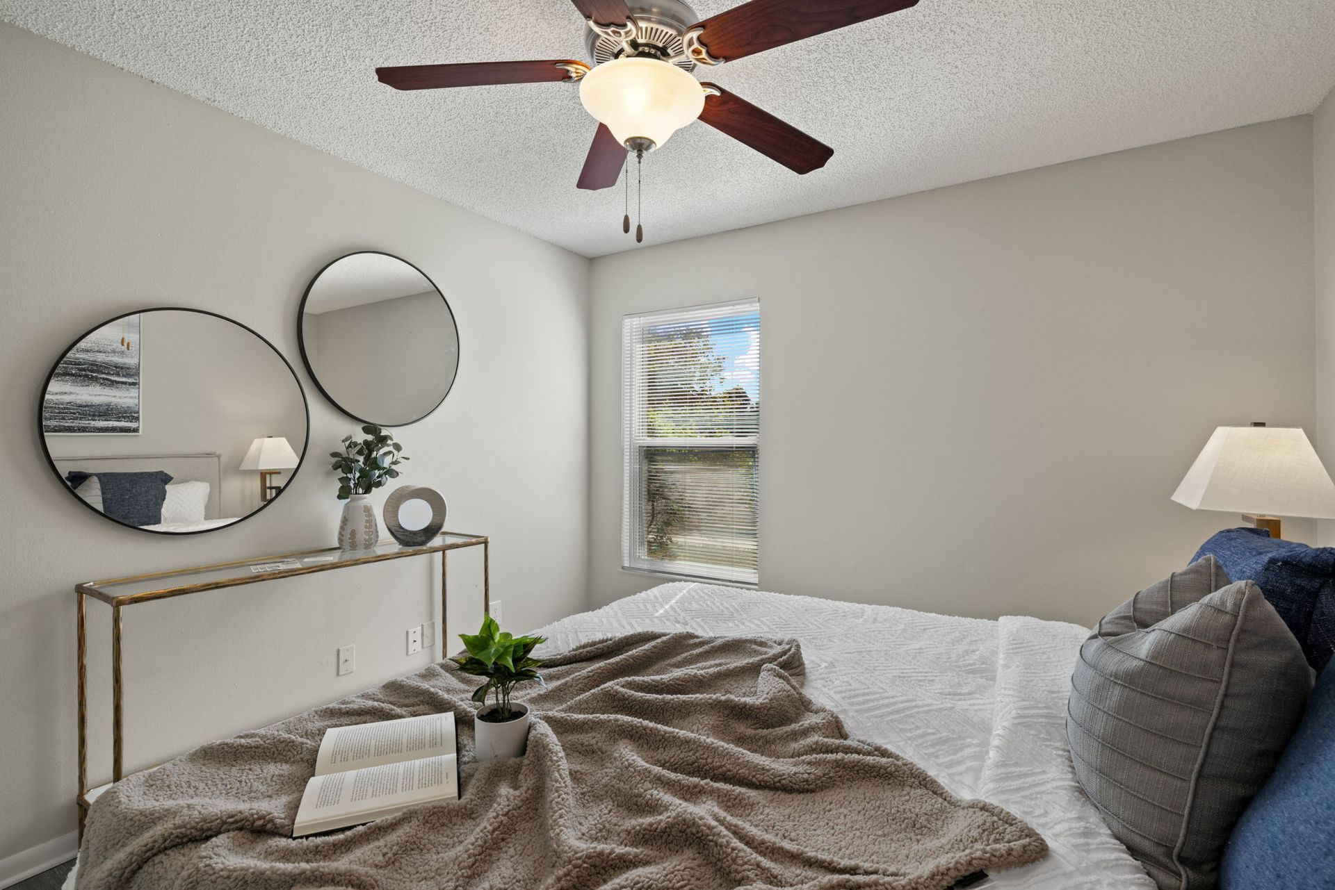 Bedroom with bed, mirrors, and ceiling fan. Neutral walls and decor.