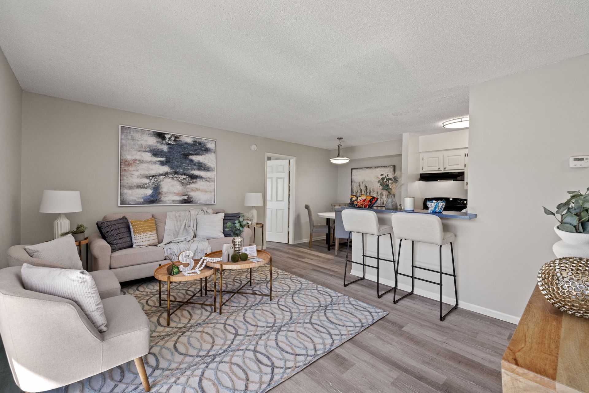 Cozy living room with sofa, armchair, coffee table, and bar seating next to kitchen area.