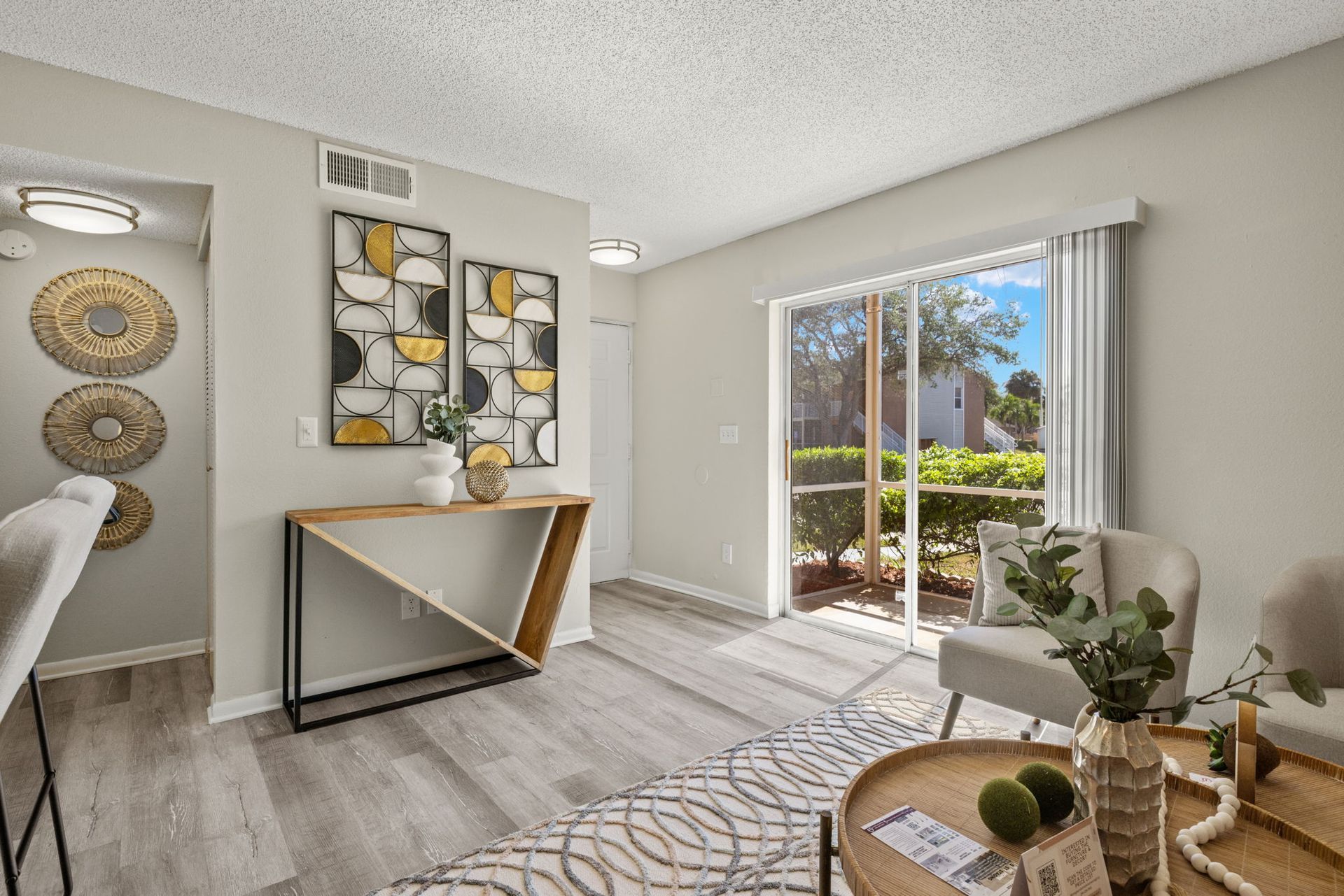 Living room with light gray walls, wood-look floors, and sliding glass door to a patio.