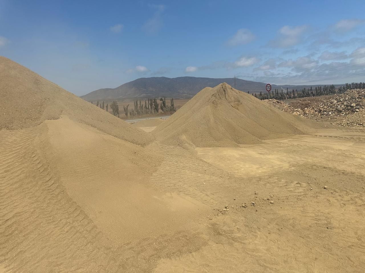 Un montón de arena en medio de un desierto con montañas al fondo.