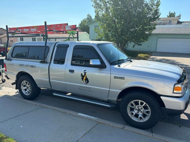 A silver truck with a canopy is parked on the side of the road.