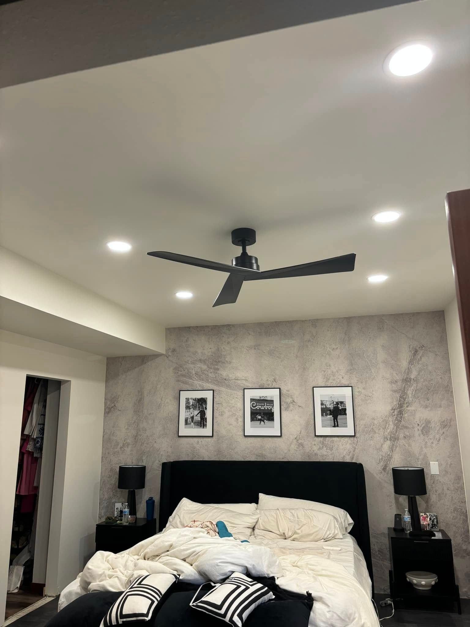 A bedroom with a bed and a ceiling fan.