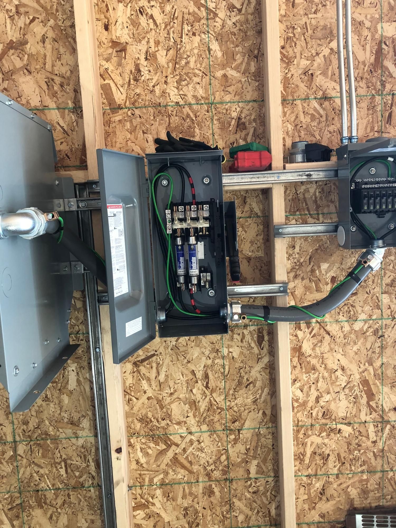 A electrical box is hanging on a wooden wall in a garage.