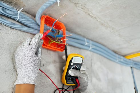 A person is using a multimeter to test electrical wires.