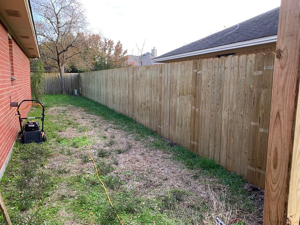 There is a lawn mower in the backyard next to a wooden fence.