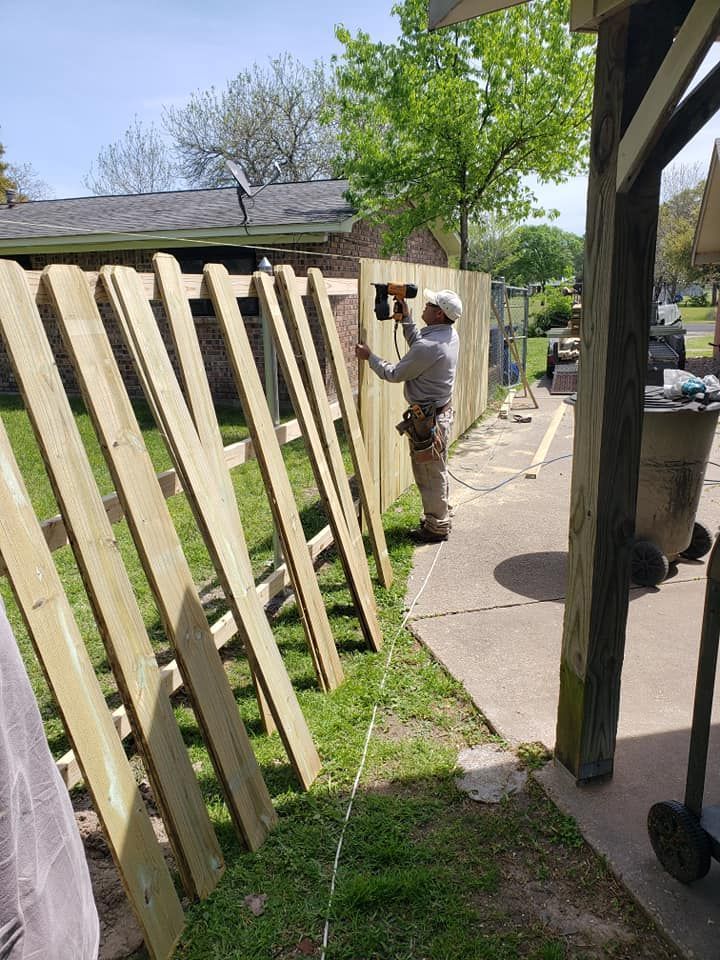 A man is installing a wooden fence.