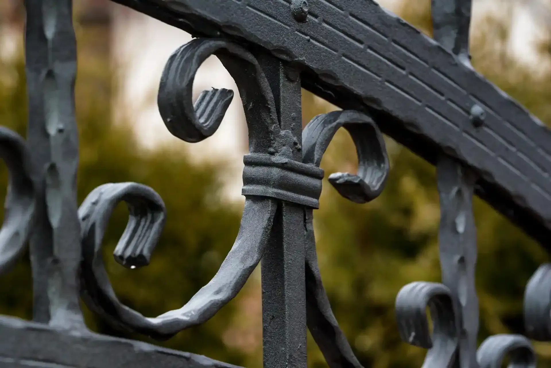 Dettaglio di recinzione in ferro battuto nero con motivi a volute, attenzione agli elementi decorativi, ambiente esterno.