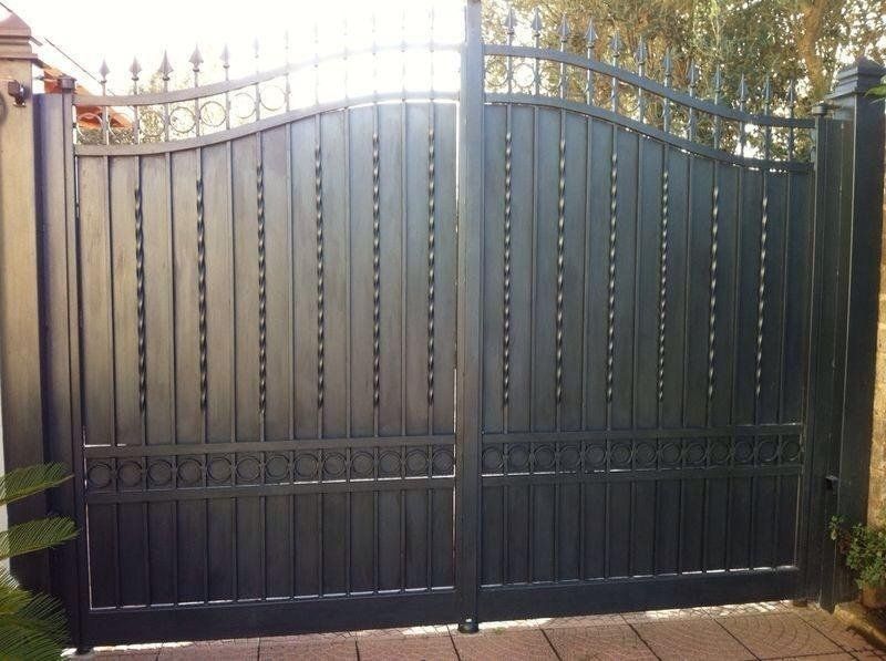 Cancello doppio in metallo nero con sbarre verticali e volute decorative.
