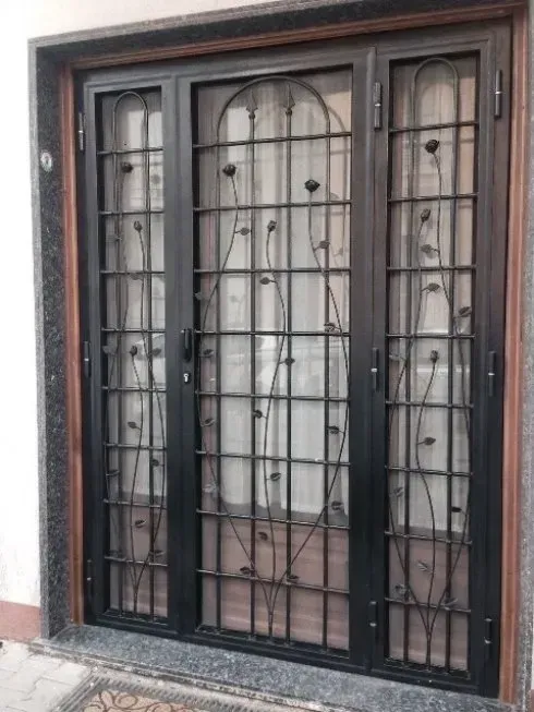 Porta con cornice in metallo nero, griglie intricate e motivi floreali.