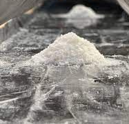 Small mounds of white salt sit on a dark, reflective surface under a protective, tent-like translucent canopy.