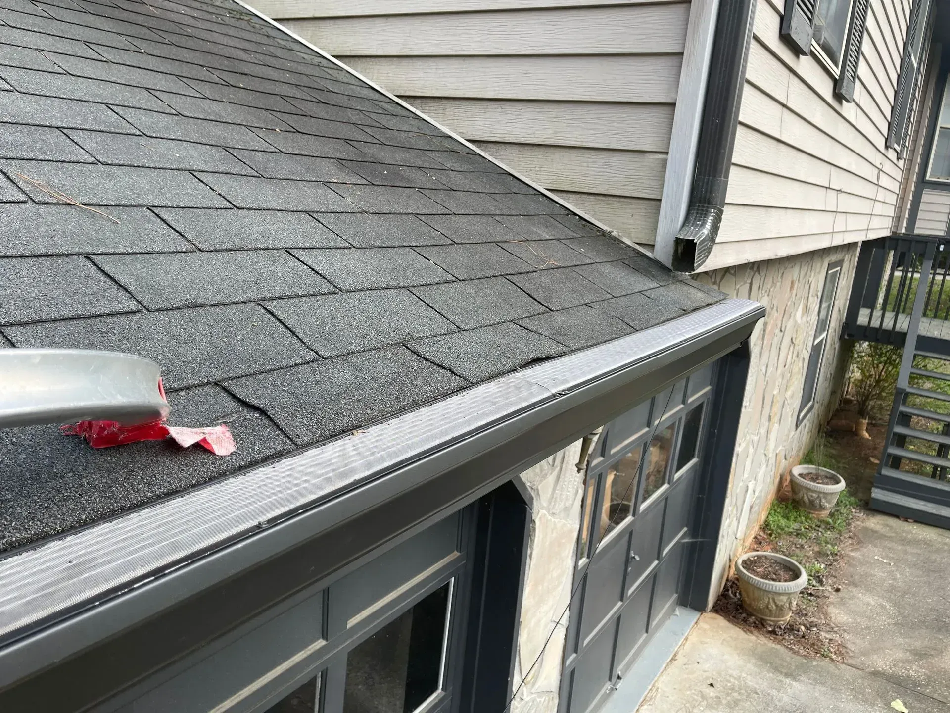 A house with a black roof and a gutter on the side of it.