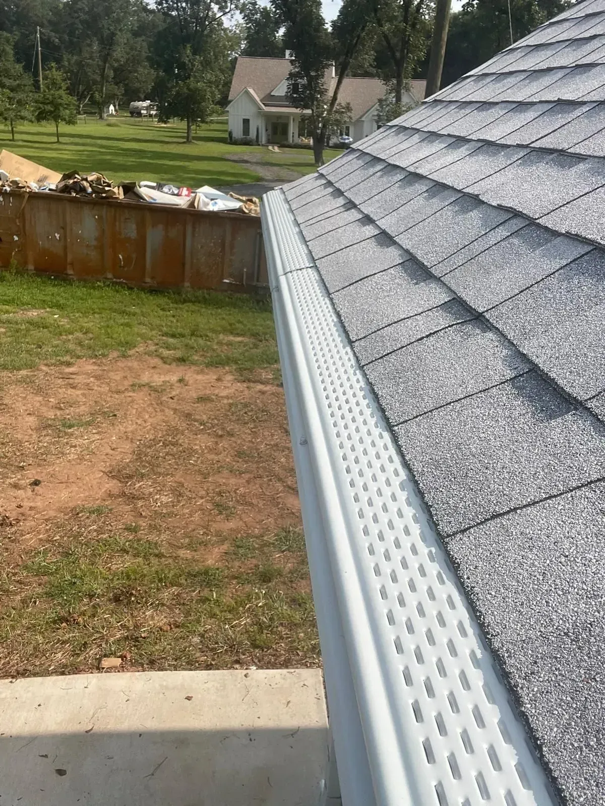 A close up of a gutter on a roof with a fence in the background.