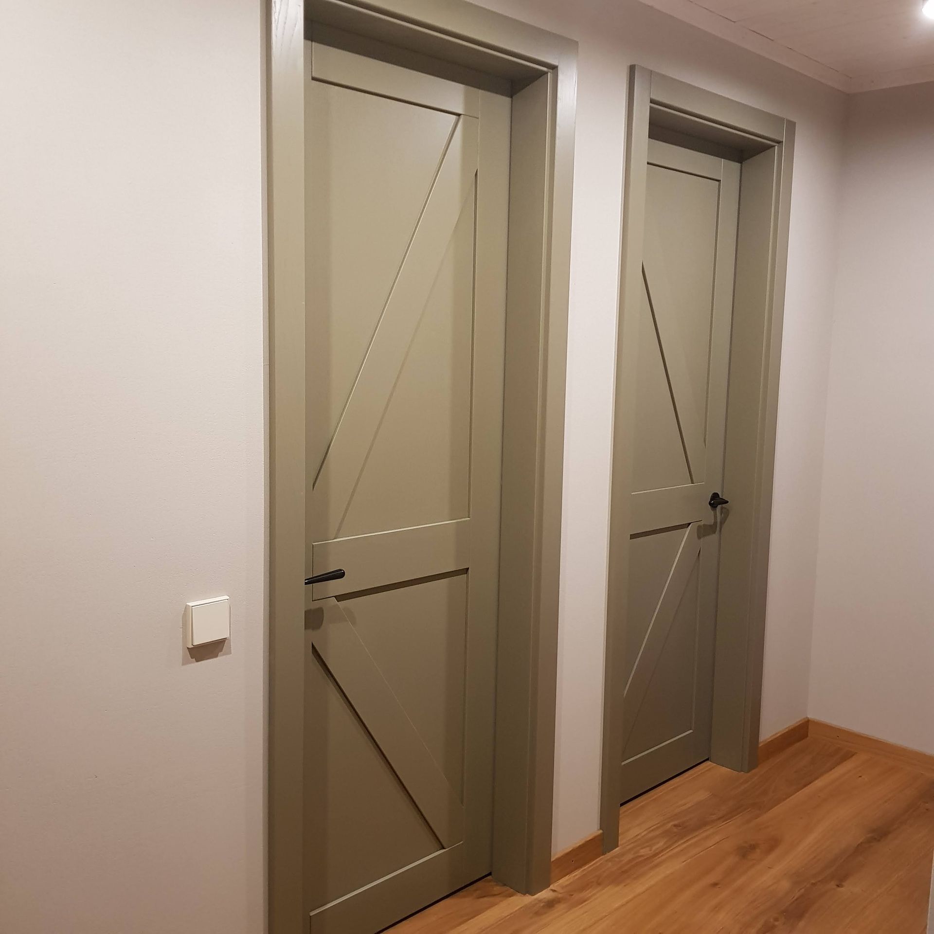Dvi žalios durys koridoriuje su medinėmis grindimis