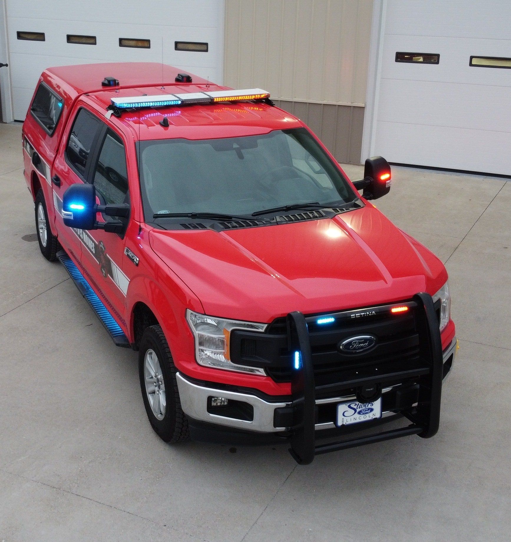 A red ford truck is parked in front of a garage