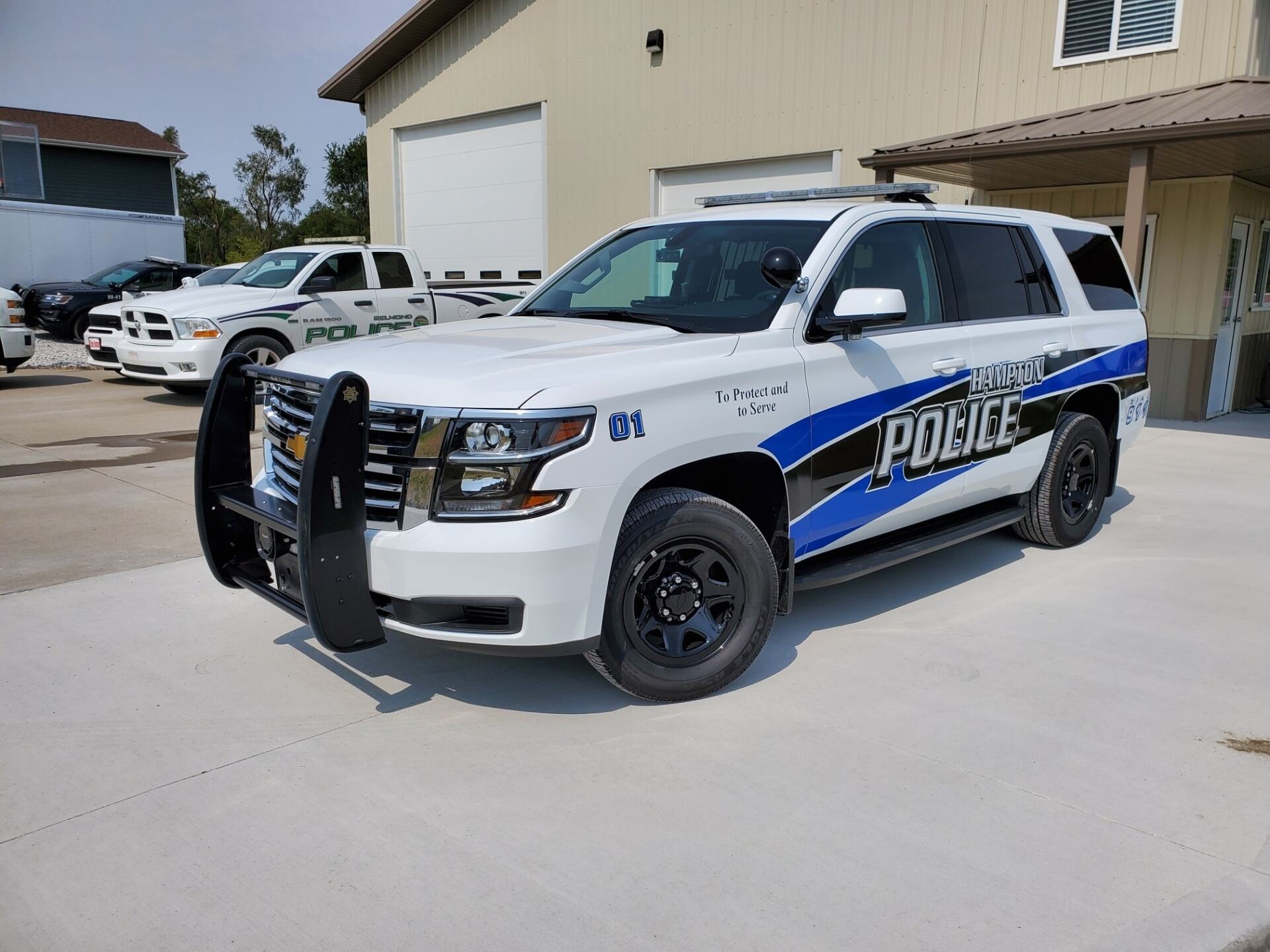 A white and blue police suv is parked in front of a building.