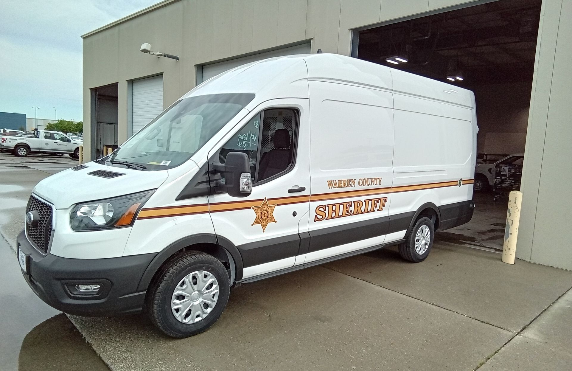 A white sheriff 's van is parked in front of a building.