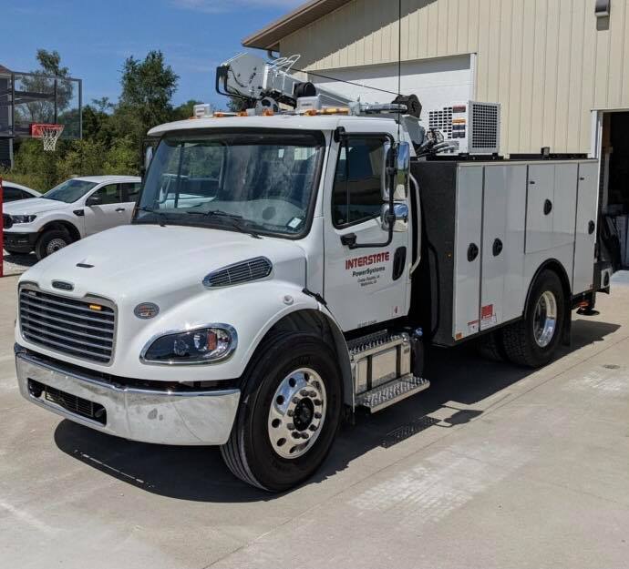 A white service truck is parked in front of a building.