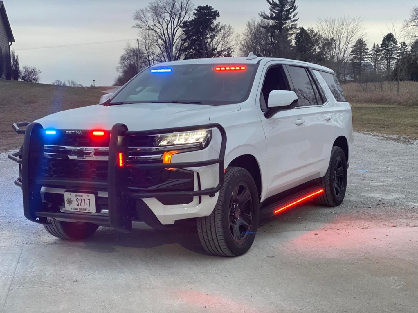 A white police suv is parked on the side of the road.
