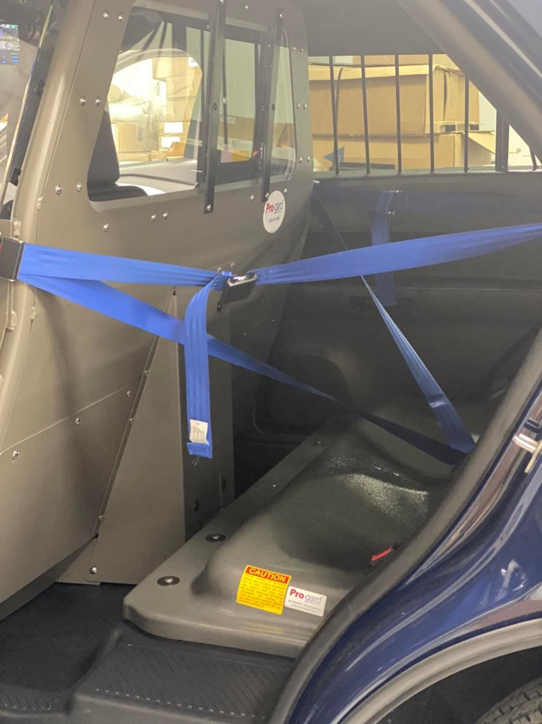 The back seat of a police car with a blue seat belt