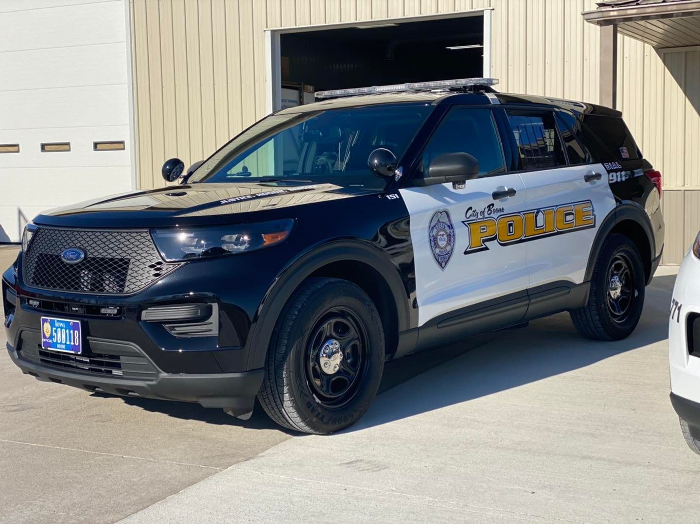 A black and white police car is parked in front of a garage.