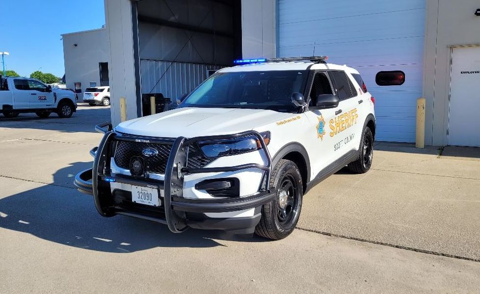 A white police car is parked in front of a garage.